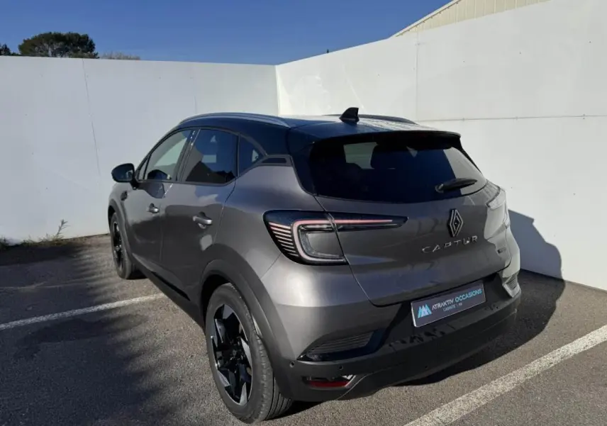 Vue 3/4 arrière droite d'un Renault Captur gris Cassiopée avec toit noir et jantes noires en aluminium.
