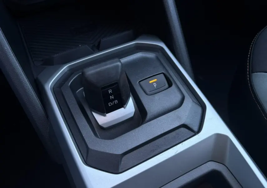 Gros plan sur la console centrale du Dacia Duster 2025, montrant le levier de vitesse automatique et le bouton de frein de stationnement.