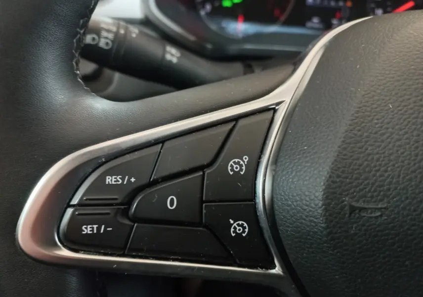 Gros plan sur les commandes du régulateur de vitesse au volant noir du Renault Captur Business gris clair 2020.