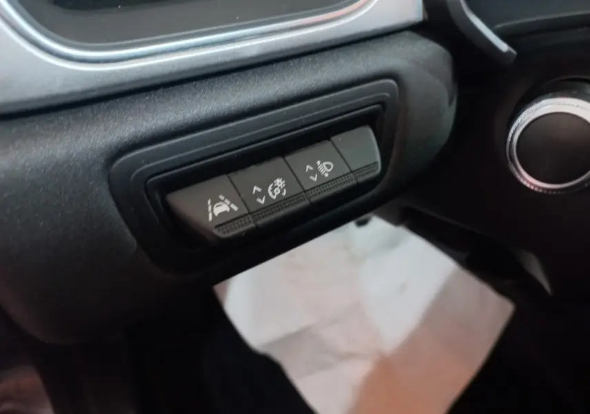 Gros plan sur les boutons de réglage d'assistance et éclairage du tableau de bord noir du Renault Captur Business gris clair.