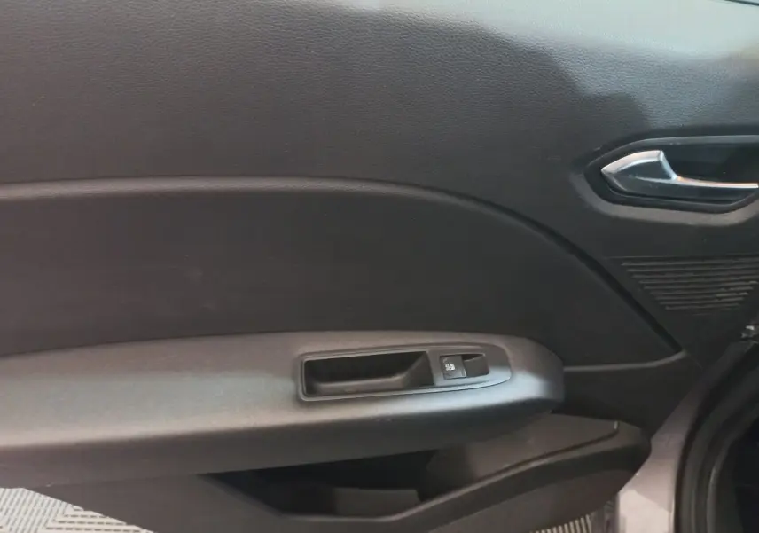 Gros plan sur la porte côté droit du Renault Captur gris clair 2020, montrant la poignée intérieure et le bouton de verrouillage des vitres.