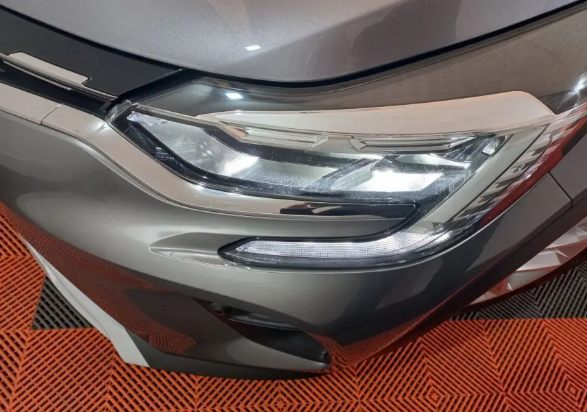 Gros plan sur le phare avant droit du Renault Captur Business gris clair, mettant en valeur ses feux LED modernes.