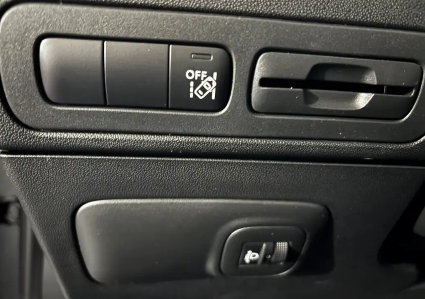 Gros plan sur les commandes de réglage des phares et ventilation du tableau de bord du Citroën C3 Aircross gris foncé 2024.