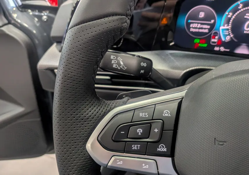 Gros plan sur le volant en cuir perforé et les commandes de régulateur de vitesse d'une Volkswagen Golf 2025.