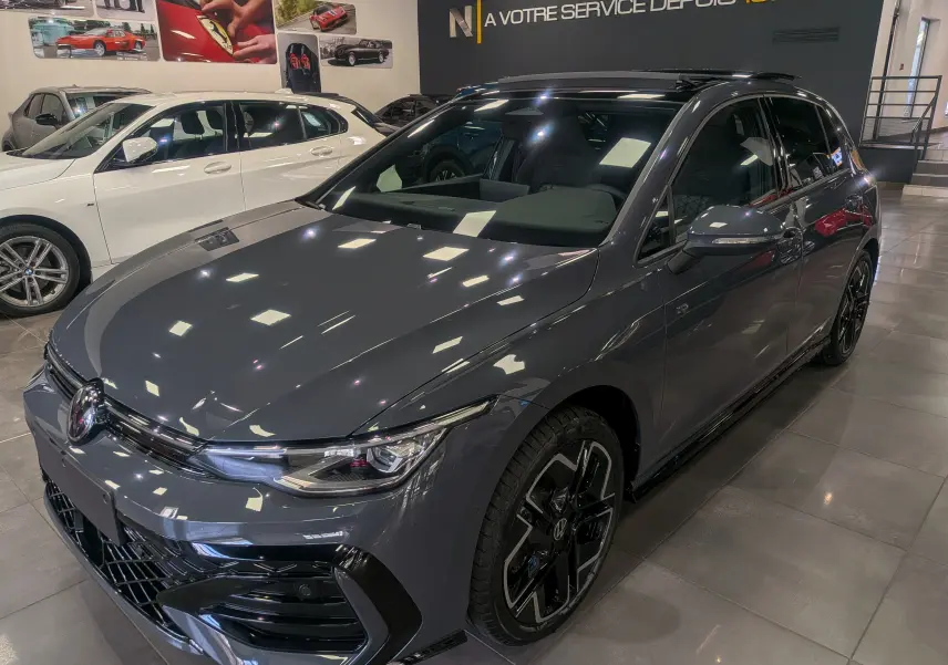 Volkswagen Golf 1.5 eTSI R-Line gris dauphin vue 3/4 avant droit en showroom avec jantes noires distinctives.