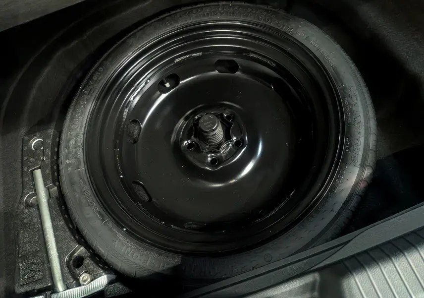 Gros plan sur la roue de secours noire dans le coffre d'une Volkswagen Golf 1.5 eTSI 2025 gris dauphin.