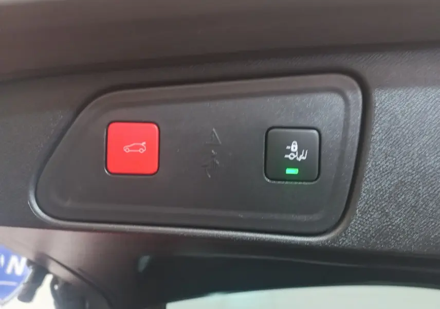 Gros plan sur les boutons d'ouverture et de verrouillage électrique du coffre dans un Peugeot 3008 gris clair 2022.