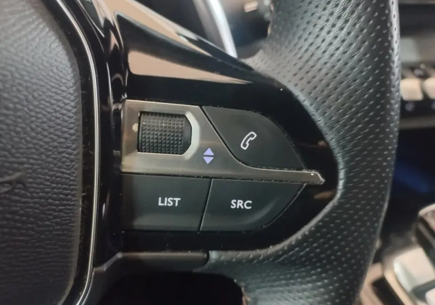 Gros plan sur les commandes gauche du volant cuir perforé du Peugeot 3008 gris clair, boutons LIST et SRC visibles.