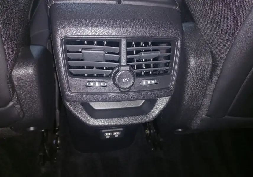 Vue rapprochée des aérateurs arrière et prise 12V du Peugeot 3008 gris clair, entre les sièges arrière en cuir noir.