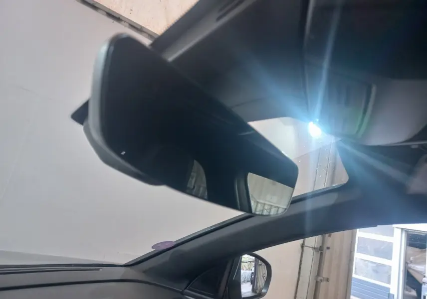 Vue intérieure du rétroviseur central et du pare-brise d’un Peugeot 3008 gris clair avec lumière naturelle entrant par le toit ouvrant.