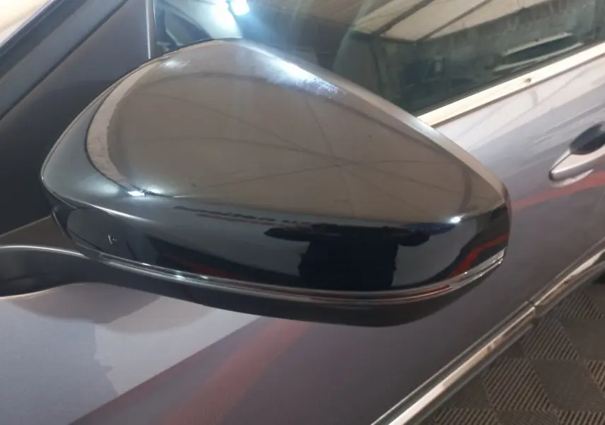 Gros plan sur le rétroviseur droit noir brillant du Peugeot 3008 gris clair, avec partie de la portière visible.