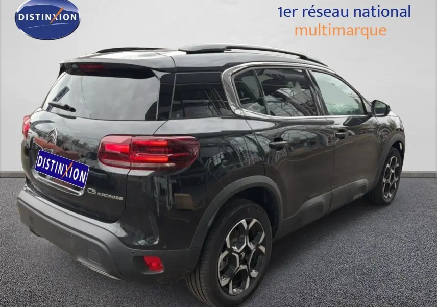Vue 3/4 arrière droite d’un Citroën C5 Aircross noir métal avec jantes bicolores et vitres teintées.