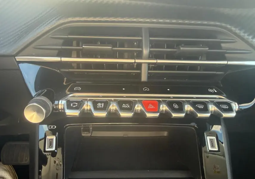 Vue rapprochée de la console centrale du Peugeot 208 Hybrid blanc 2024, avec boutons de commande et aérateurs noirs.