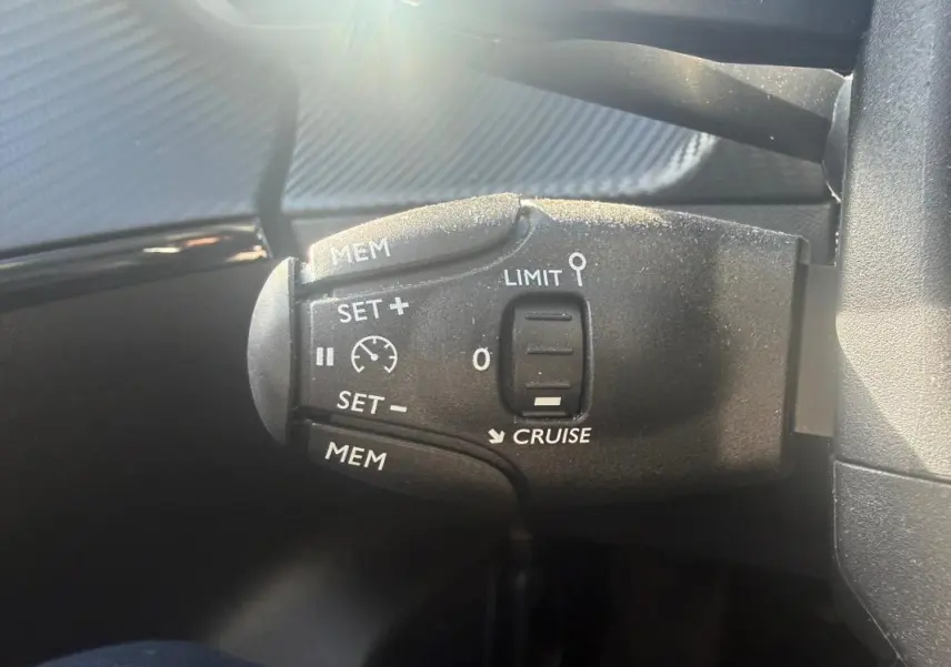Gros plan sur la commande de régulateur de vitesse du Peugeot 208 blanc Hybrid 110 e-DCS6 Allure 2024.