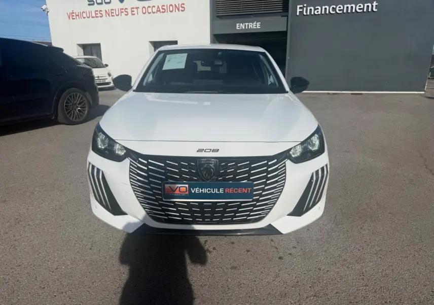 Vue de face d'une Peugeot 208 Hybrid 110 e-DCS6 Allure blanche 2024 avec calandre noire et phares LED distinctifs.