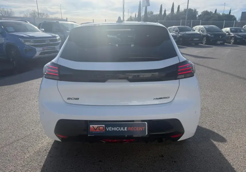 Vue arrière d'une Peugeot 208 Hybrid blanche 2024 avec feux arrière LED et bande noire distinctive.