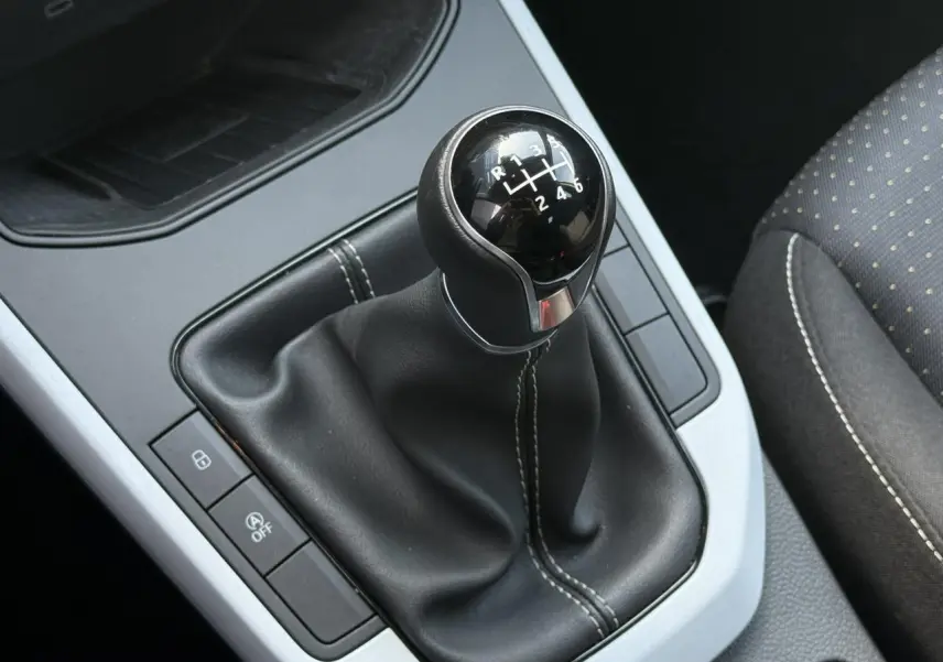 Gros plan sur le levier de vitesses manuel noir avec coutures blanches dans l’habitacle du SEAT Arona TSI 115 Style.