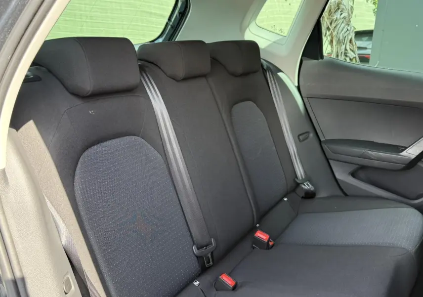 Vue intérieure de la banquette arrière noire du SEAT Arona 2025, avec ceintures de sécurité et appuie-têtes visibles.