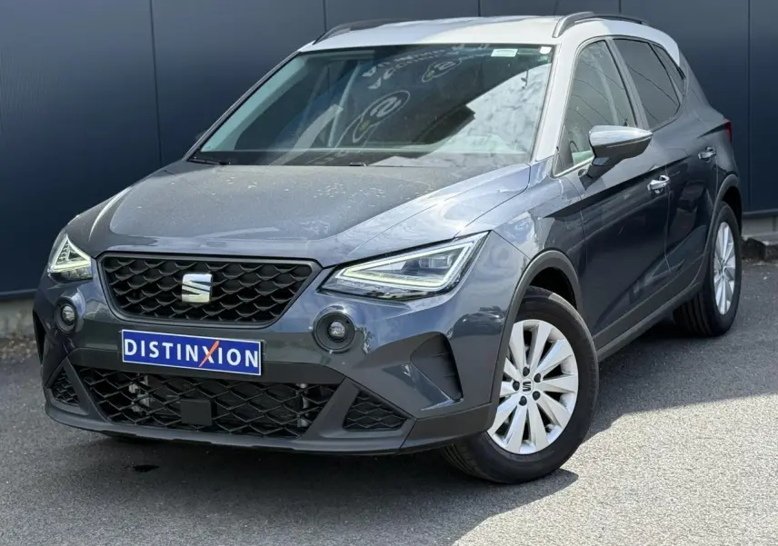 Vue 3/4 avant droite d'un SEAT Arona 2025 gris magnétique avec toit blanc et jantes alliage 16 pouces.