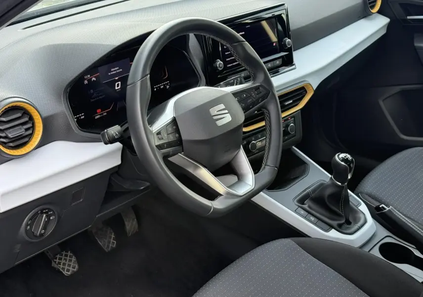 Vue intérieure du poste de conduite du SEAT Arona TSI 115 Style 2025, volant multifonction et levier de vitesse manuel visibles.