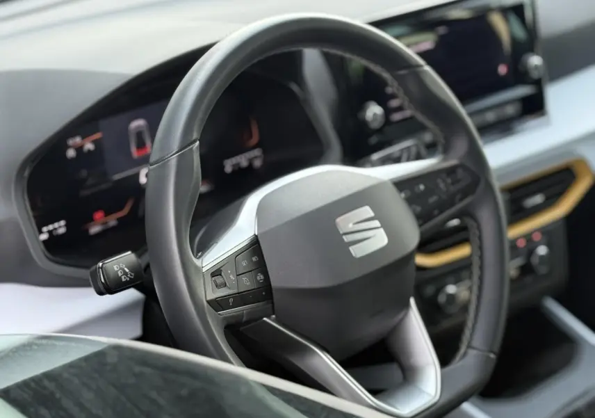 Vue rapprochée du volant noir et du tableau de bord digital du SEAT Arona TSI 115 Style 2025, intérieur moderne.