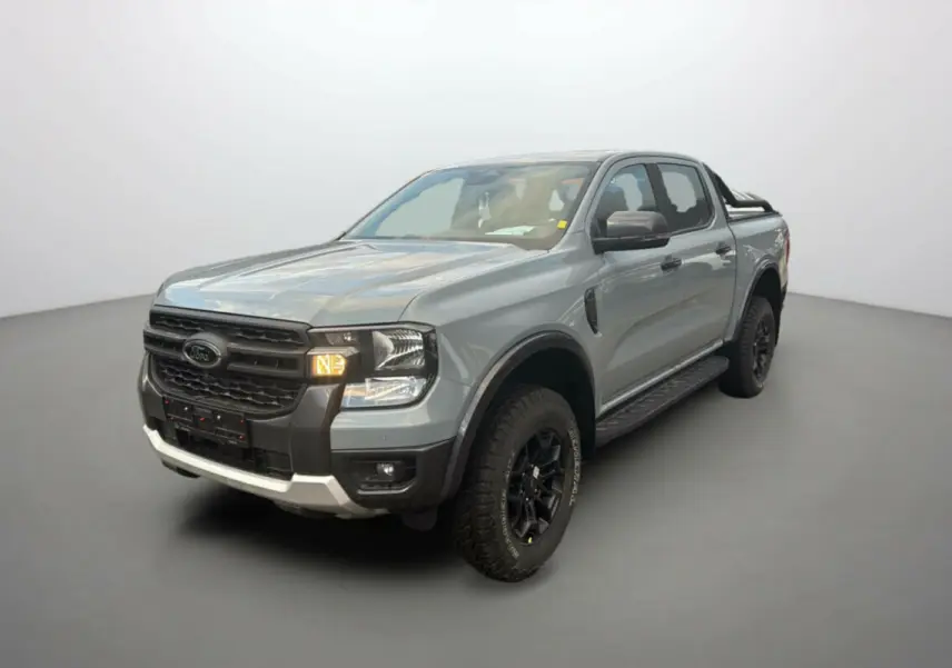 Ford Ranger gris commandeur en 3/4 avant droit avec arceaux noirs et marchepieds visibles sur fond neutre.