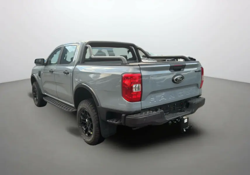 Ford Ranger gris commandeur vu en 3/4 arrière droit avec arceaux noirs et attelage visible.