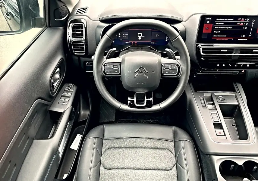 Vue intérieure frontale du poste de conduite noir du Citroën C5 Aircross 2025 avec volant multifonction et écran tactile.