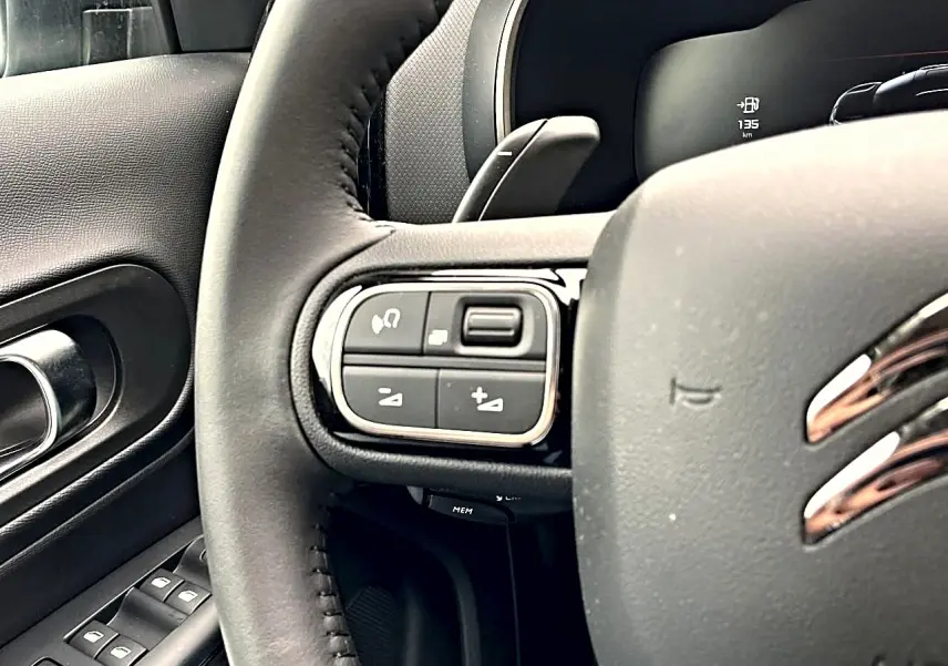 Gros plan sur le volant noir de la Citroën C5 Aircross 2025, avec commandes intégrées côté gauche et logo chromé visible.