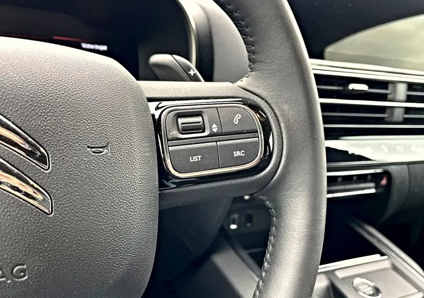 Gros plan sur le volant noir du Citroën C5 Aircross 2025 avec commandes intégrées côté droit et tableau de bord en arrière-plan.