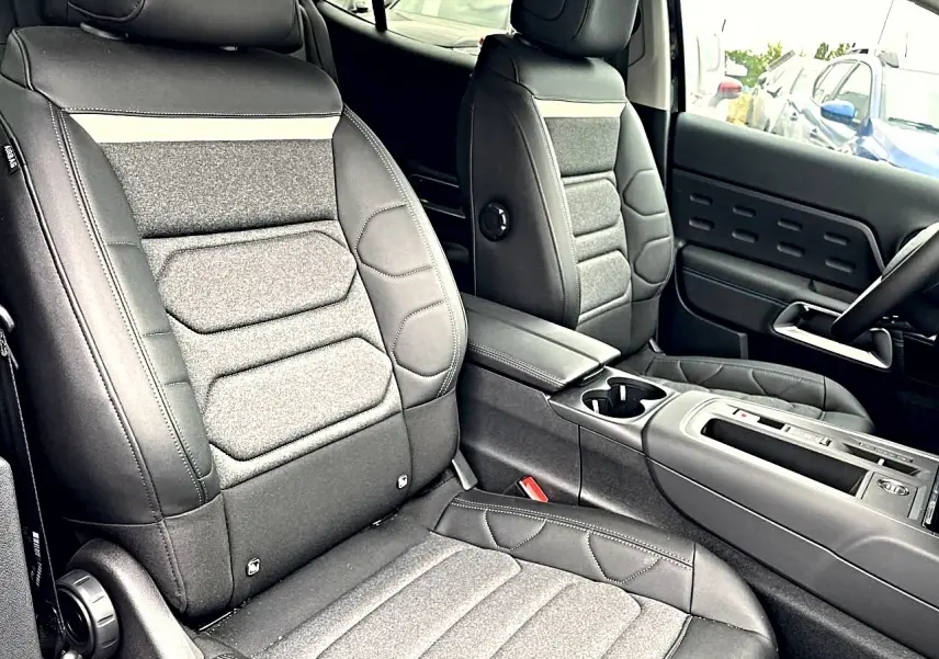 Vue intérieure rapprochée des sièges avant noirs et gris du Citroën C5 Aircross avec accoudoir central et console.