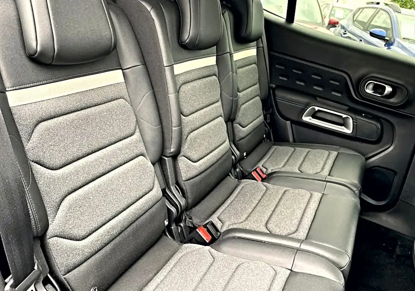 Vue latérale des sièges arrière gris et noirs du Citroën C5 Aircross 2025 avec appuie-têtes et ceintures visibles.