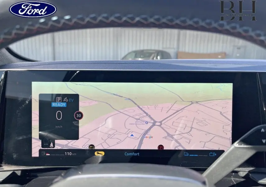 Vue intérieure du tableau de bord du Ford avec écran tactile affichant la navigation GPS et informations de conduite.