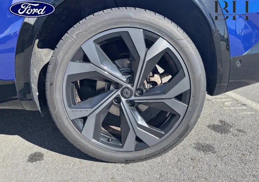 Gros plan sur la roue arrière droite bleu Iron du Renault Austral 1.2 E-Tech avec jante alu noire esprit Alpine.
