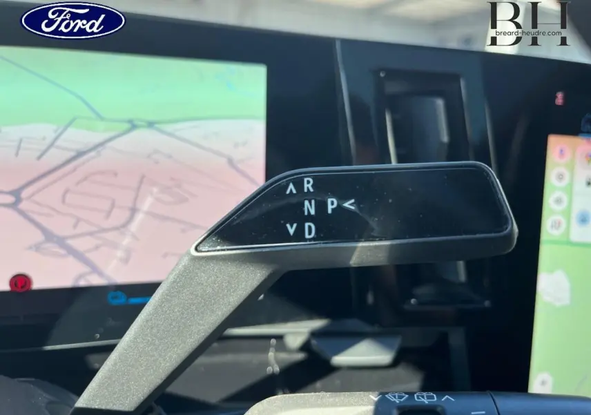 Le véhicule Renault Austral bleu Iron est vu de l'intérieur, avec un focus sur le levier de vitesses automatique et l'écran tactile GPS.