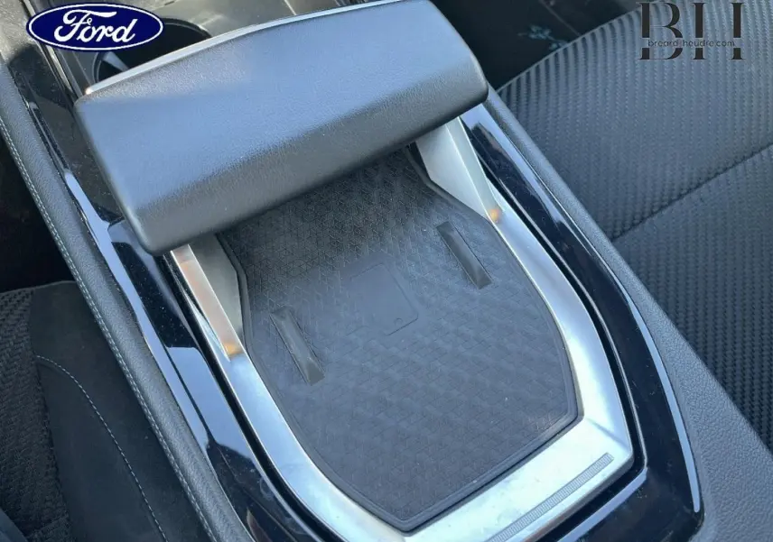 Gros plan sur la console centrale noire avec accoudoir et surface de recharge, intérieur tissu carbone/Alcantara bleu.