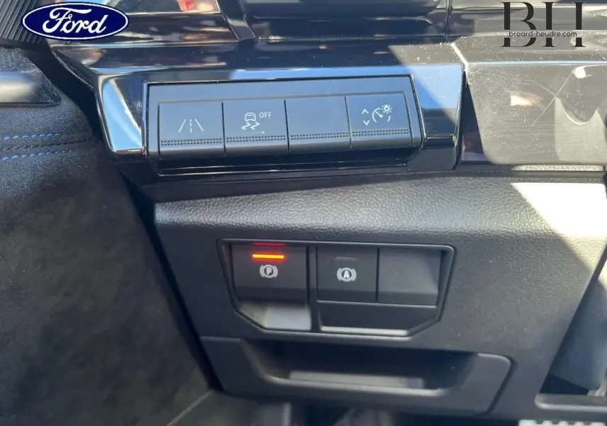 Panneau de commandes au tableau de bord avec boutons d'aide à la conduite et frein de parking électrique activé.