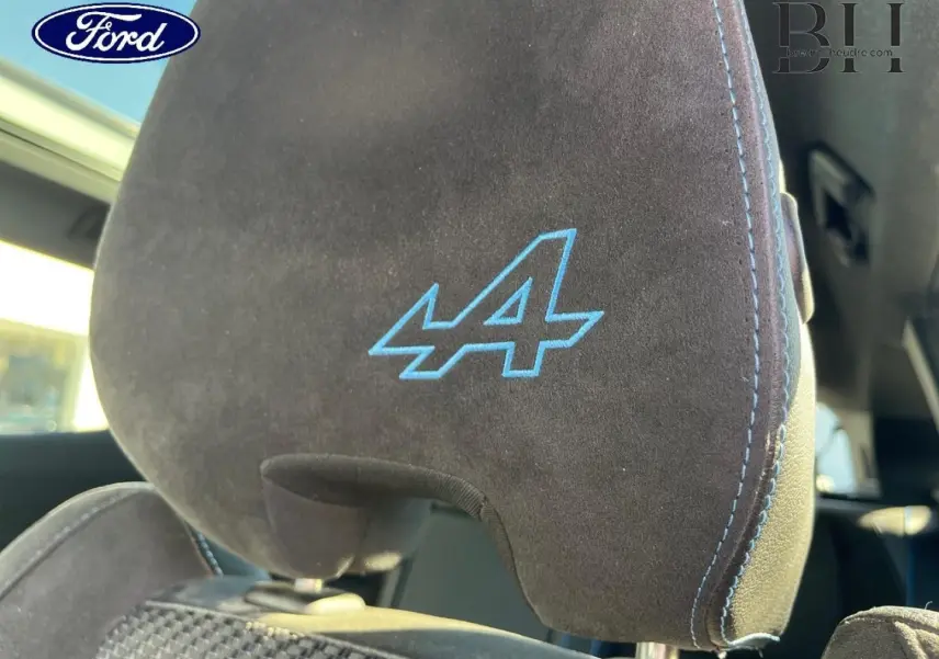Gros plan sur l'appui-tête avant en alcantara noir avec logo Alpine bleu et surpiqûres bleues du Renault Austral Bleu Iron.