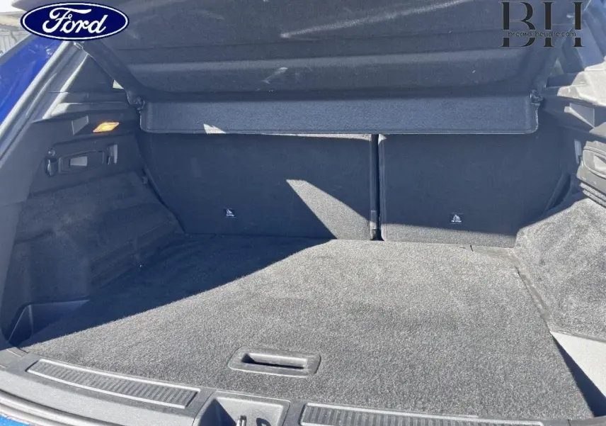 Coffre ouvert vu de l'arrière d'un Renault Austral Bleu Iron, montrant un espace de chargement propre et spacieux.