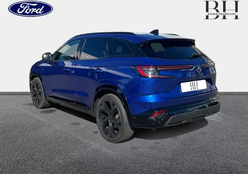 Vue 3/4 arrière droite d'un Renault Austral 2023 bleu Iron avec jantes noires et becquet arrière sportif.