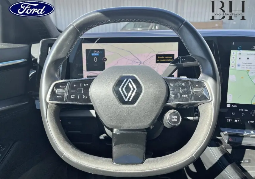 Vue rapprochée du volant cuir et alcantara avec logo Renault, écran tactile et commandes intégrées visibles.
