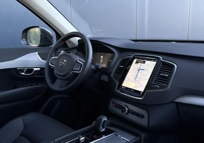 Vue intérieure côté conducteur du Volvo XC90 2024 avec écran tactile vertical et volant multifonction noir.