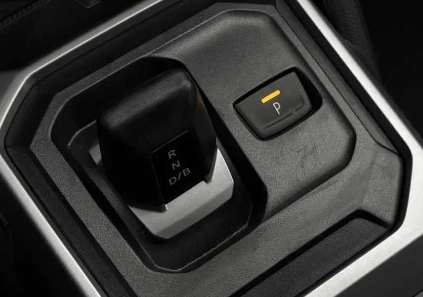 Gros plan sur le levier de vitesses et bouton de parking du Dacia Duster gris, intérieur moderne et épuré.