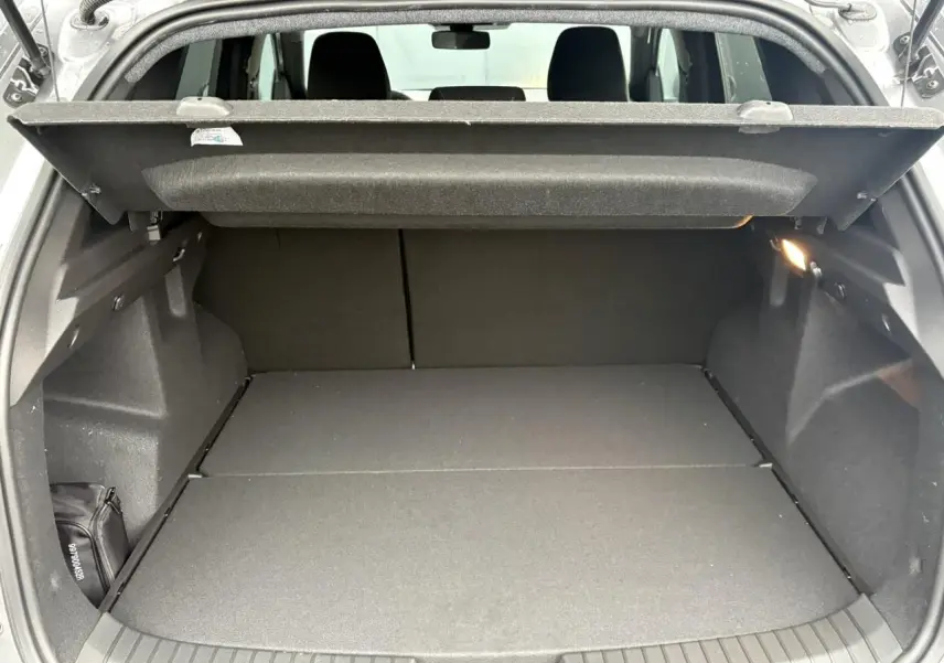 Coffre ouvert du Dacia Duster gris schiste, vue arrière montrant l'espace de chargement et la tablette cache-bagages.