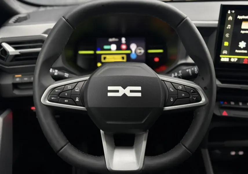 Vue frontale du volant noir du Dacia Duster 2026 avec commandes intégrées et tableau de bord digital en arrière-plan.