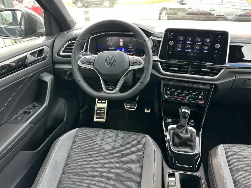 Intérieur du Volkswagen T-Roc 2025 essence gris, vue centrée sur le volant multifonction et la console centrale moderne.