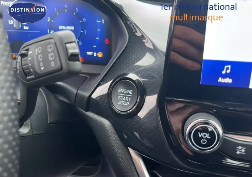 Détail intérieur du tableau de bord du Ford Puma gris magnétique 2024, avec bouton start/stop et commandes audio visibles.