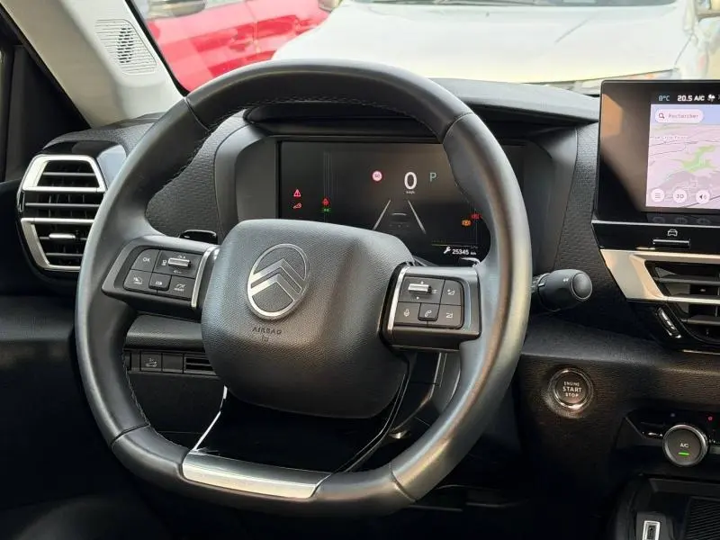 Vue intérieure centrée sur le volant du Citroën C4 X 2025, avec tableau de bord numérique et écran tactile à droite.