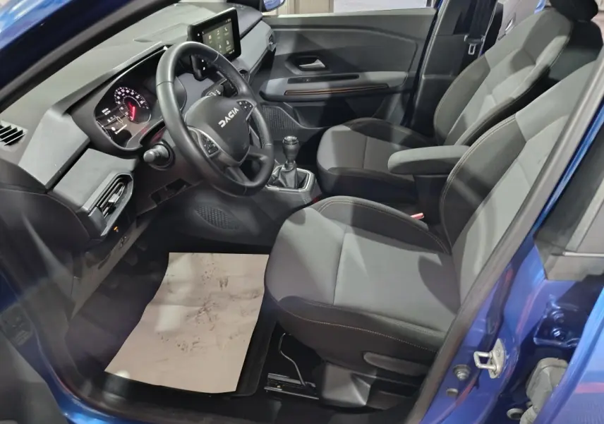 Vue intérieure côté conducteur de la Dacia Sandero Extreme+ TCe 110 2024 bleu, volant cuir et écran tactile central visible.