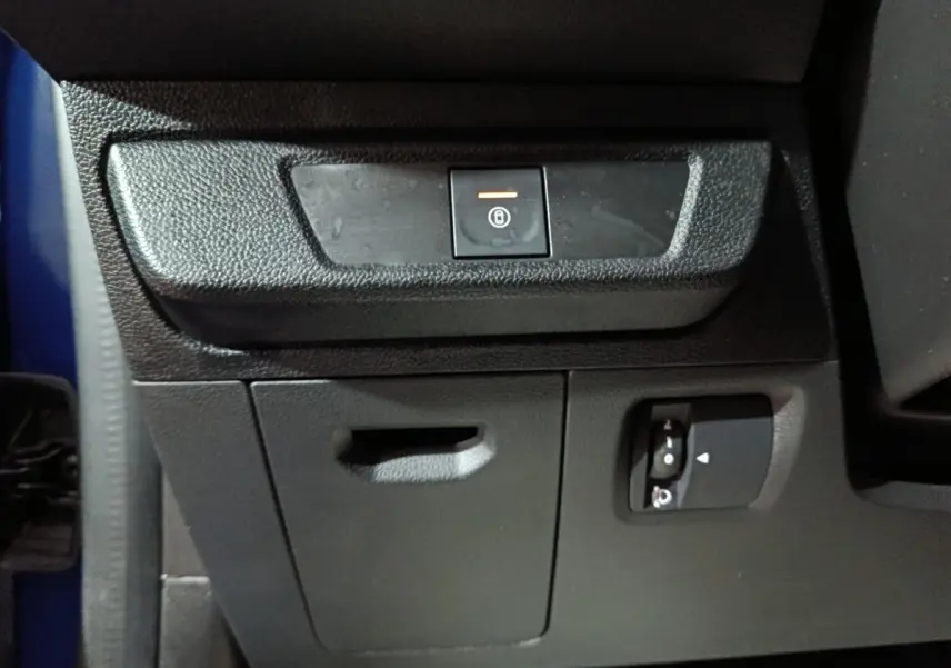 Détail intérieur montrant le bouton de condamnation centralisée sur la console côté conducteur d'une Dacia Sandero bleu 2024.